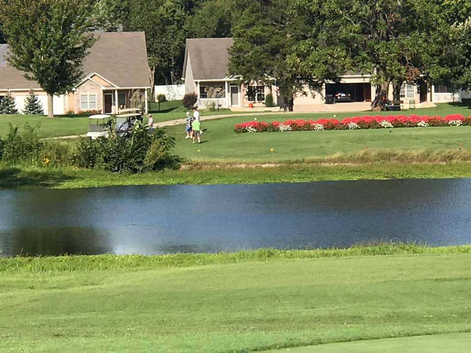 A group of golfers play alongside a pond on the course at Ottawa